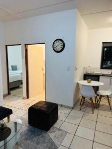 a living room with a clock on the wall and a table at 3-Bedrooms Apartment in Bushmill Amorosa in Roodepoort +24 photos