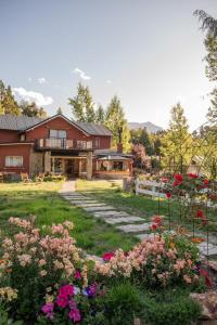 a house with a yard with flowers in front of it at Equs Posada de Campo in San Carlos de Bariloche