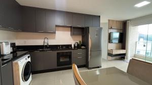 a kitchen with a stainless steel refrigerator and a dishwasher at Apê 18º andar | Churrasqueira vista mar + Piscina in Itapema
