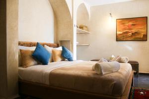 a bedroom with a large bed with blue pillows at Maison D'hôtes IMINIGRAN & Spa in Ouarzazate