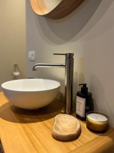 a bathroom sink with a white bowl on a wooden counter at De Poverleute in Kortrijk