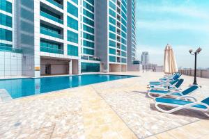a pool on the roof of a building with lounge chairs at Luxury Oceanfront Fully Furnished 2BR! in Ajman 