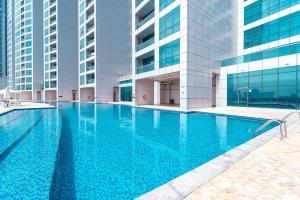 a swimming pool in front of a building with tall buildings at Luxury Oceanfront Fully Furnished 2BR! in Ajman 