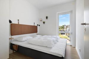 a bedroom with a bed with white sheets and a window at 4797-Allinge-Havnevej-14-C-1-th in Allinge