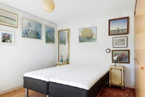 a bedroom with a large white bed and pictures on the wall at 5634-Svaneke-Bolshavn-29-A in Svaneke