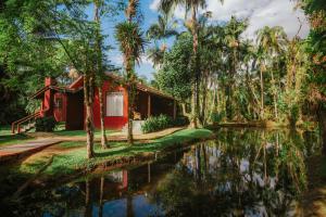a red house next to a body of water at Pousada Hakuna Matata in Morretes
