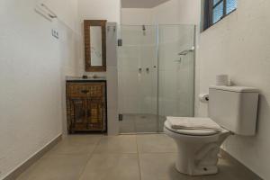 a bathroom with a toilet and a glass shower at Pousada Hakuna Matata in Morretes