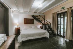 a bedroom with a white bed and a staircase at Pousada Hakuna Matata in Morretes
