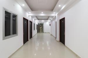 un couloir d'un bâtiment aux murs blancs et aux portes noires dans l'établissement Hotel O Shri Tirupati, à Nalmatha