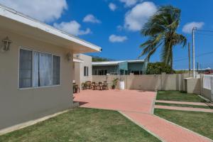 a house with a patio and a palm tree at Hotel experience with daily housekeeping and laundry in Oranjestad
