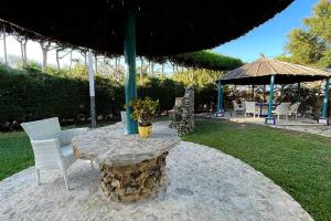 a stone table with two chairs and an umbrella at Alojamiento Turístico Nacarum in El Palmar