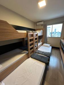 a room with three bunk beds and a window at Edifício Frente Mar Apto lateral in Balneário Camboriú
