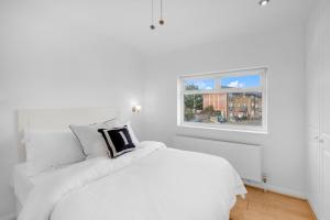 Un dormitorio blanco con una cama blanca y una ventana. en 4 Bed - Sleeps 8 - Free Parking - Garden, en Dagenham