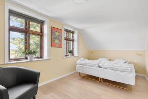 a bedroom with a bed and a chair and windows at 3691-Nexo-Stensebyvejen-32 in Neksø