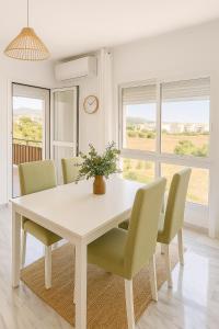 a white dining room table with chairs and a potted plant at Las Viñaas in Vélez-Málaga