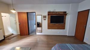 a room with a tv on the wall and a bedroom at Suíte Aconchegante, bem localizada in Vitória