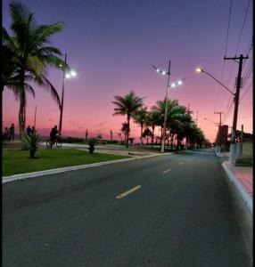 eine leere Straße mit Palmen und Sonnenuntergang in der Unterkunft Hause DK praia grande in Praia Grande