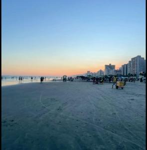 eine Gruppe von Menschen am Strand bei Sonnenuntergang in der Unterkunft Hause DK praia grande in Praia Grande