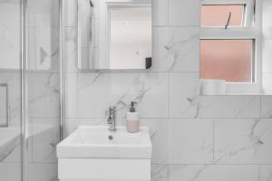 Un baño blanco con lavabo y espejo. en 4 Bed - Sleeps 8 - Free Parking - Garden, en Dagenham 12 fotos más