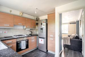 eine Küche mit Holzschränken und einem Edelstahlkühlschrank in der Unterkunft Cozy 2-Bed Home in Middleton in Middleton