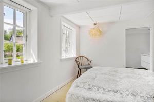 a white bedroom with a bed and a chair at 5525-Svaneke-Bolshavn-19 in Svaneke