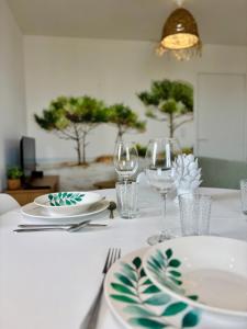 einen Tisch mit Tellern und Weingläsern darauf in der Unterkunft La Pinède, Proche gare, Centre ville, Netflix in Bourgoin