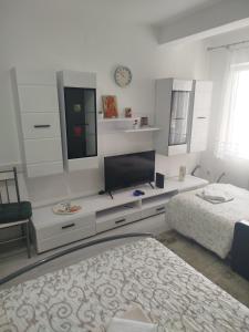 a white bedroom with a bed and a tv and a desk at Vea in Banja Koviljača