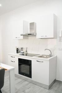 a white kitchen with a sink and a stove at Camurrìa Appartamenti in Bronte +27 photos