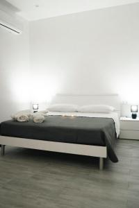 a white bedroom with a large bed with black sheets at Camurrìa Appartamenti in Bronte