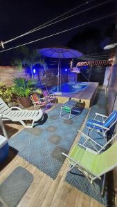 a group of chairs and umbrellas on a swimming pool at night at Casa de temporada do Mr Bim in Cabo Frio