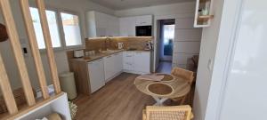 a small kitchen with white cabinets and a table at Le Mulaty Cozy in Tossiat +3 photos