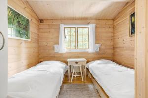 two beds in a wooden room with a window at 1444-Aakirkeby-Poseregardsvejen-15 in Vester Sømarken