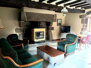a living room with a fireplace with chairs and a table at Le Logis d'Aliénor - Baie du Mont St-Michel in Baguer-Pican