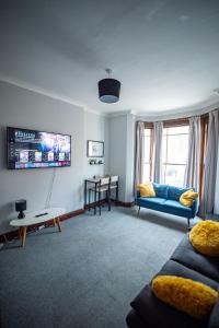 a living room with a blue couch and a tv at One BR Flat By Eason Stays Short Lets & Serviced Accommodation Lowestoft With Free Parking in Lowestoft