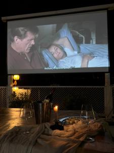 ein Fernsehbildschirm mit einem Mann und einer Frau, die in einem Bett liegen in der Unterkunft ATHOS CAPE in Pyrgadikia