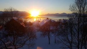 a winter sunset with the sun setting over a lake at Warm and cozy apartment in Tromsø, free parking and close to both airport and nature in Tromsø