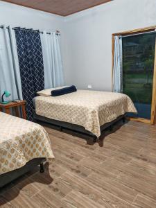 a bedroom with two beds and a window at Habitaciones y Cabañas El Sauce in Tela