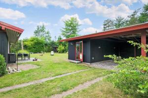a black house with a red roof and a yard at LF16181-Logstor-Abelonesvej-19 in Løgsted