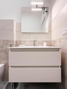 a white bathroom with a sink and a mirror at Camurrìa Appartamenti in Bronte