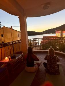 deux femmes assises sur un porche regardant le coucher du soleil dans l'établissement Green Sea Villa - Wild Orange Dubrovnik, à Zaton