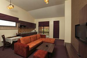 a living room with an orange couch and a kitchen at Family Hotel - Restaurant Ring in Montana