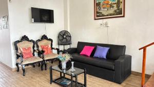 a living room with a black couch and two chairs at casa del sol in Tena