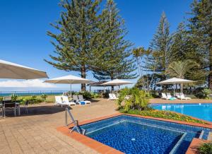 a swimming pool with chairs and umbrellas at a resort at Nautilus Beach Apartment 109 in Coffs Harbour +1 photo