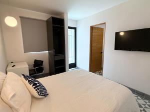 ein Schlafzimmer mit Bett und Flachbildfernseher in der Unterkunft Suites Heriberto Frías in Mexiko-Stadt