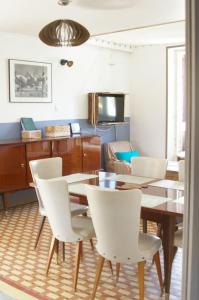 a dining room with a table and white chairs at Villa de 1926, plage de sable fin à 200m, proche commerces in Jullouville-les-Pins