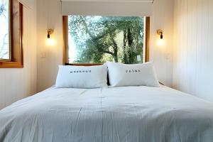 1 cama con 2 almohadas frente a una ventana en Escapada en pareja en un rincón del bosque, en San Martín de los Andes
