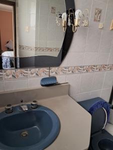 a bathroom with a blue sink and a mirror at Cozy, fashionable and stylish room in Quito