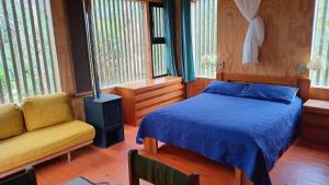 a bedroom with a bed and a chair and windows at Posada IRSIS in La Pedrera