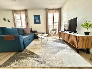 セリにあるCosy Apartment Near Disneyland Parisの青いソファと薄型テレビのあるリビングルーム