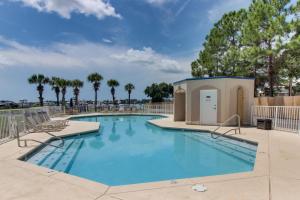 a swimming pool at a resort with chairs and trees at Harbor Cove #410 in Orange Beach